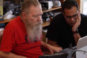 Two men look at a screen. One has a BCI that allows him to communicate via brain waves.